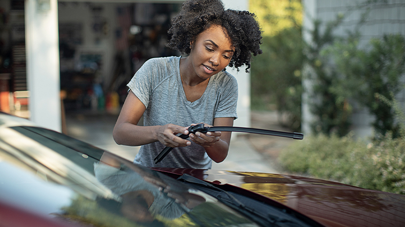 a woman replaces a wiper blade on her vehicle
