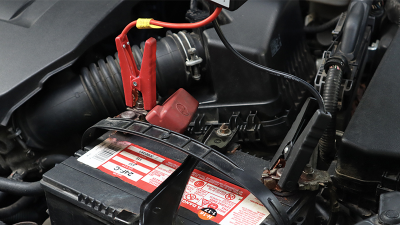 jump box cables connected to an old battery
