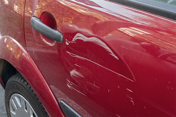 a red car with a dent and white scratch in the right rear door